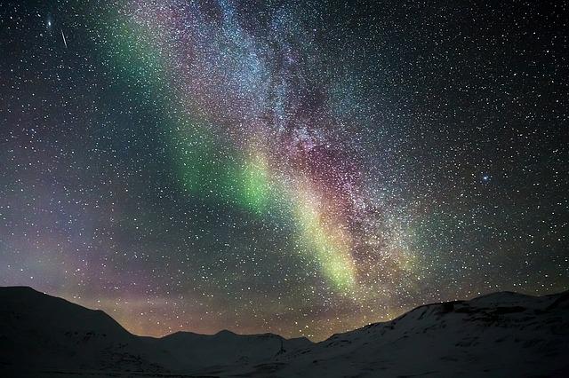 imagem de uma aurora de tons verde, vermelho e azul e uma noite estrelada